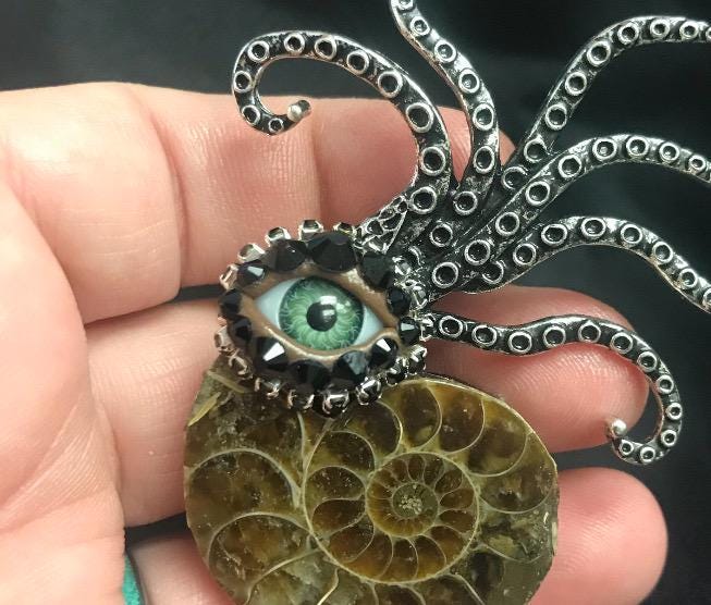 Ammonite Fossil Brooch: Surreal Green Eye Rhinestone Pin